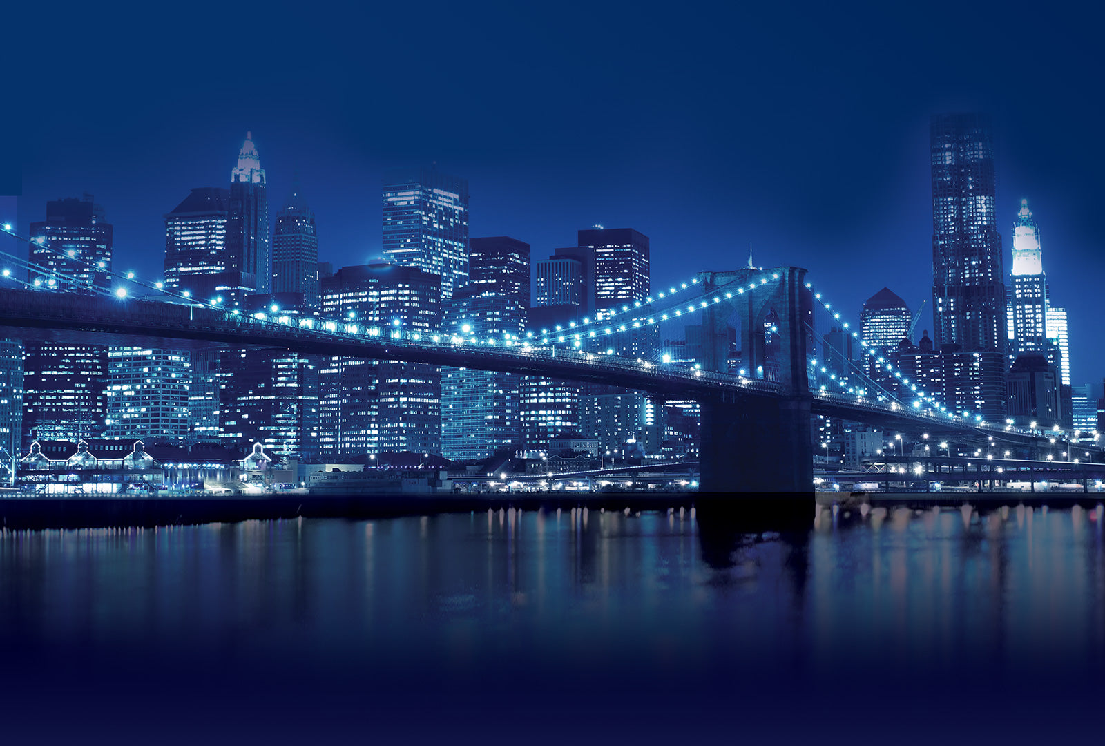 Brooklyn Bridge and New York City skyline at night with blue tint