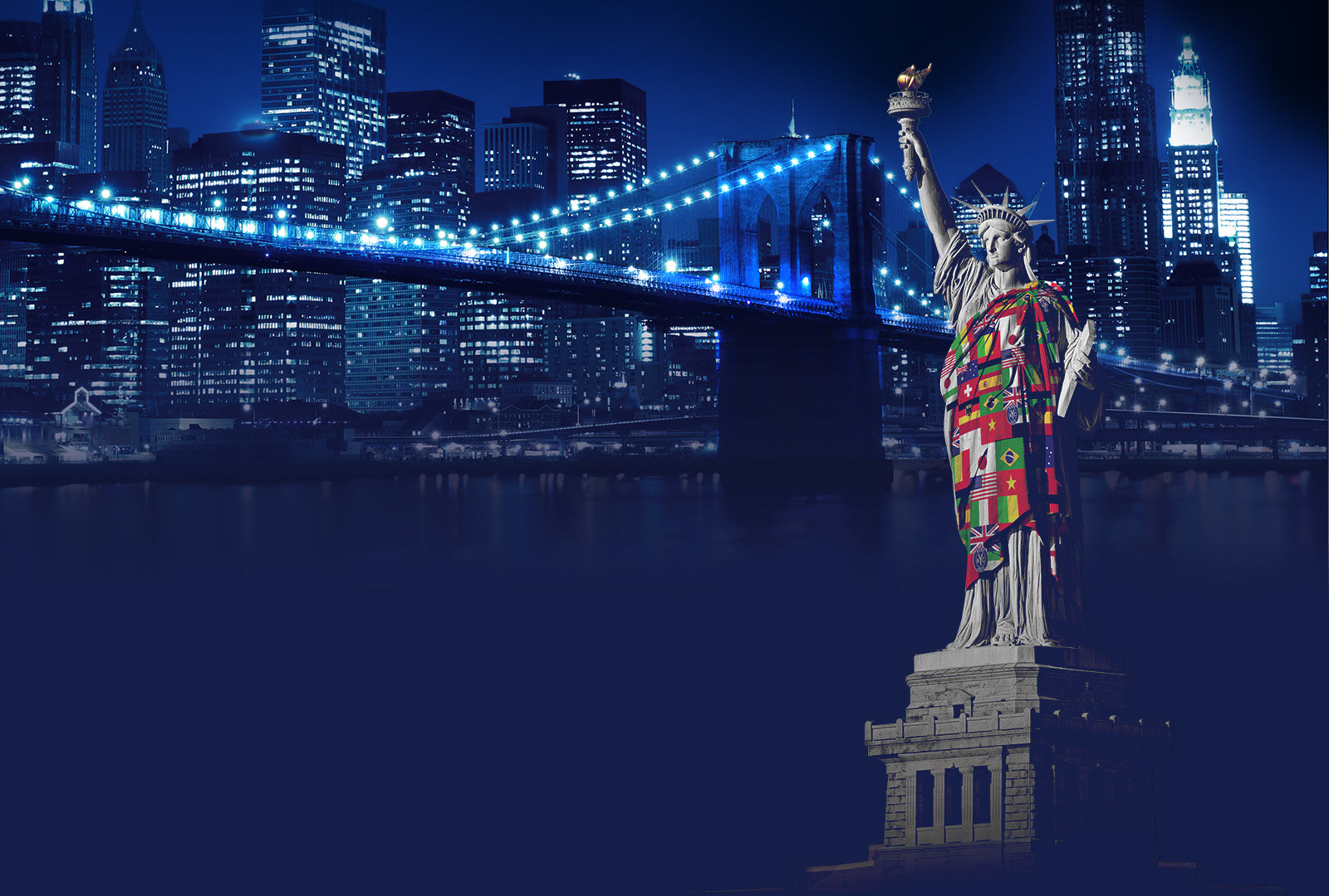 Statue of Liberty with a colorful quilt draped over it, illuminated against a city skyline at night.