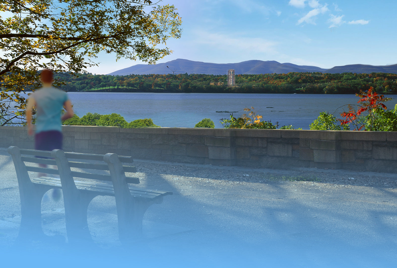 Person standing by a river with a scenic view of the water and mountains.