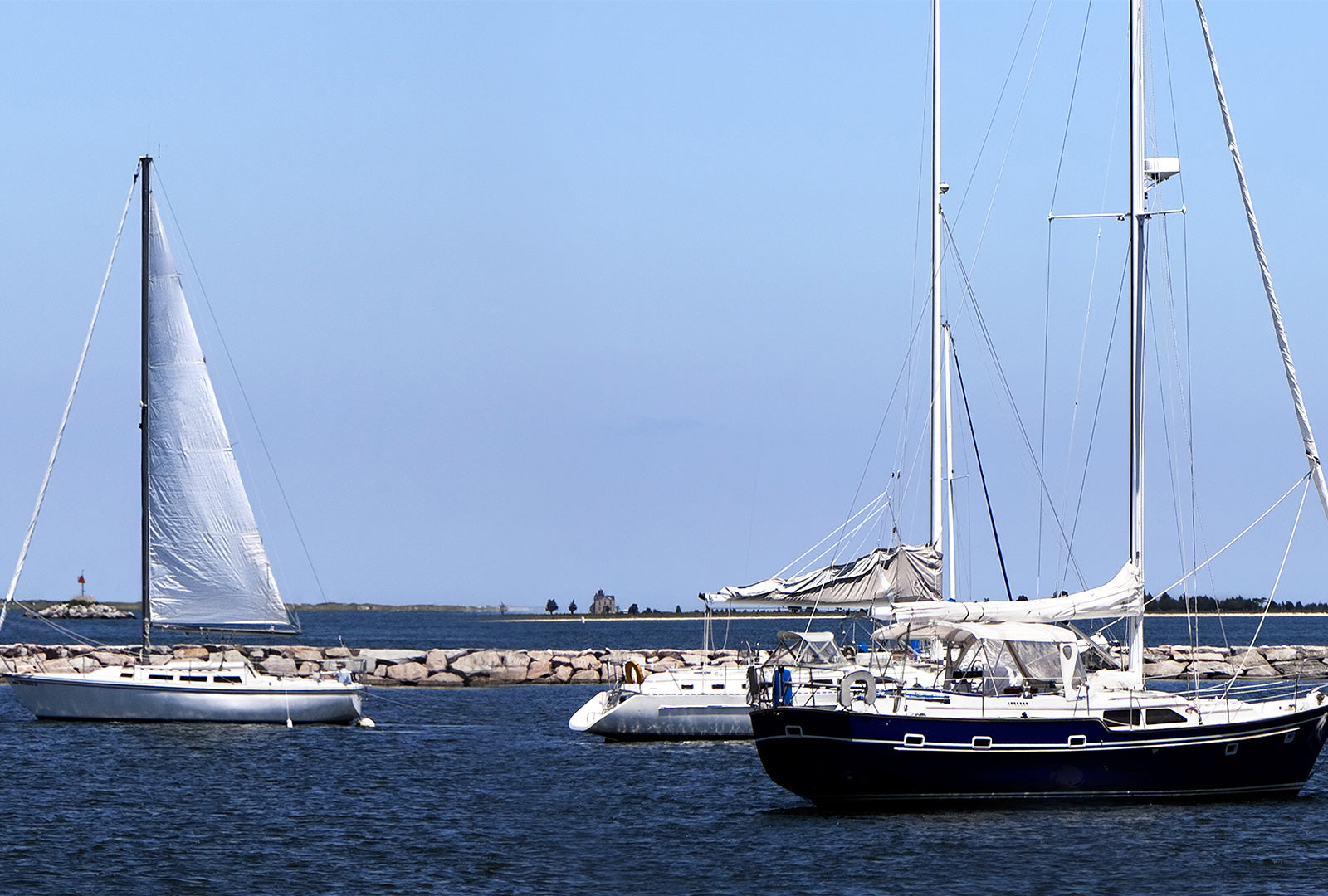 Two sailboats on a body of water with a clear blue sky.